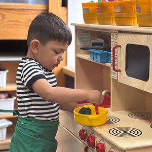 Preschool student at a play kitchen in a classroom